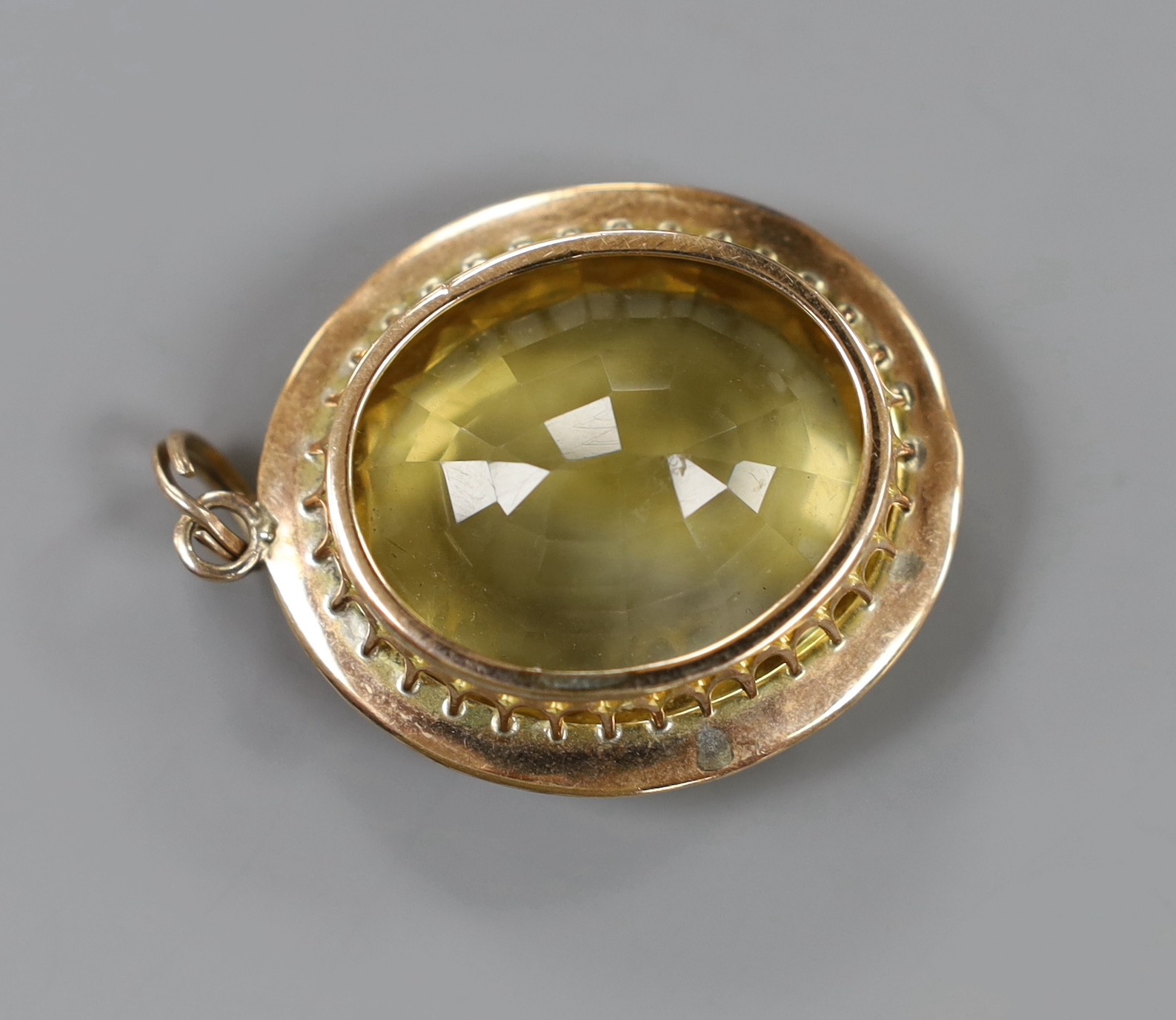 A yellow metal mounted oval cut citrine pendant, overall 49mm, gross weight 23.3 grams.